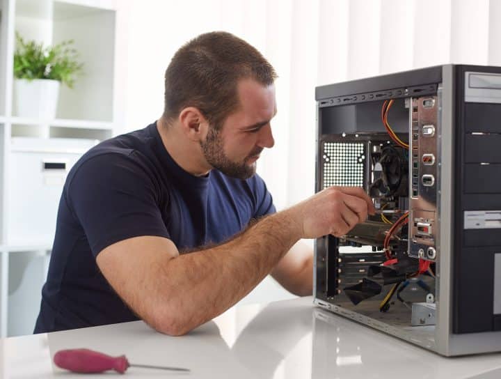 Technician repairing a desktop computer with precision tools
