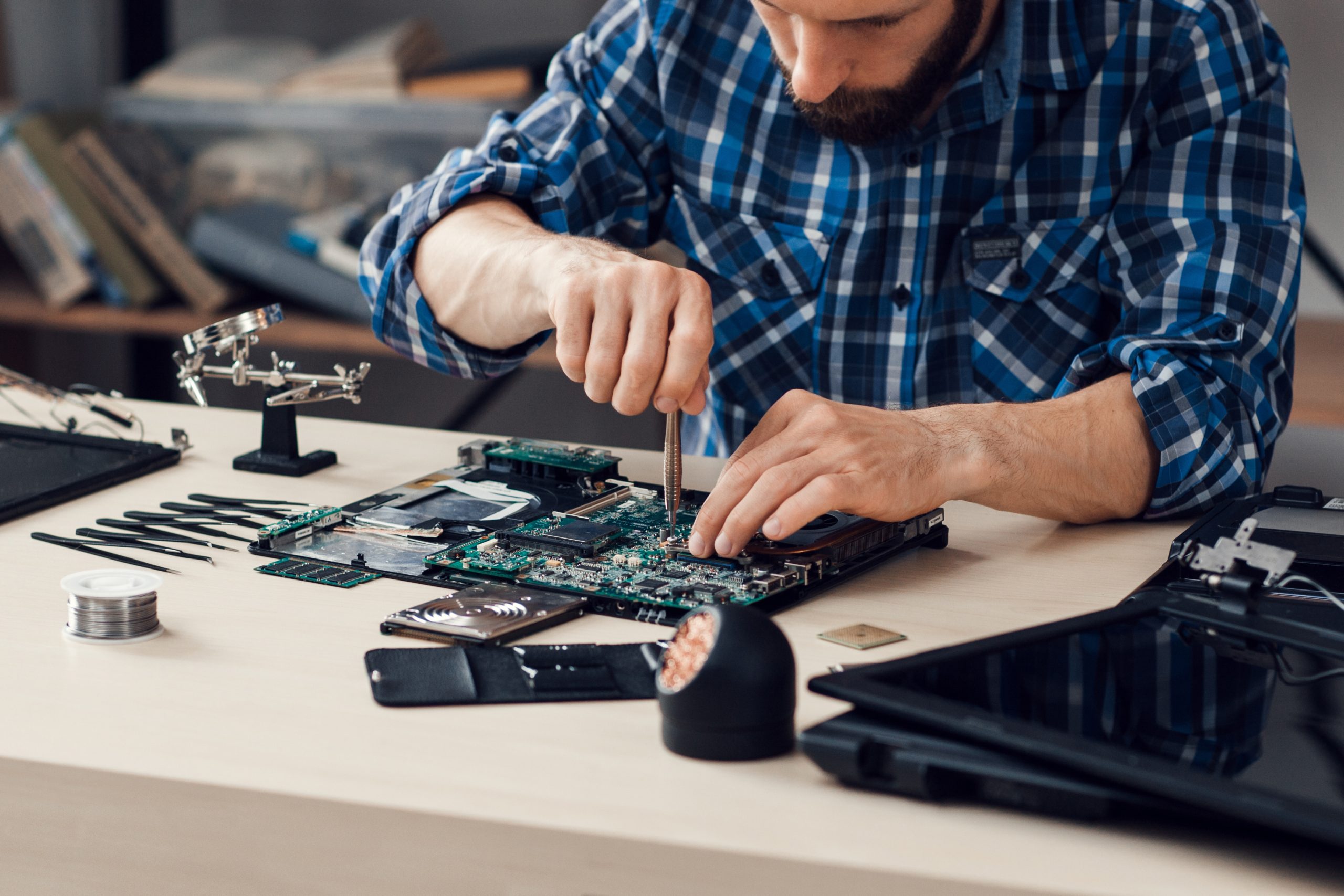 Professional Laptop Motherboard Repair in Denver Technician repairing a laptop motherboard on a workbench with precision tools.