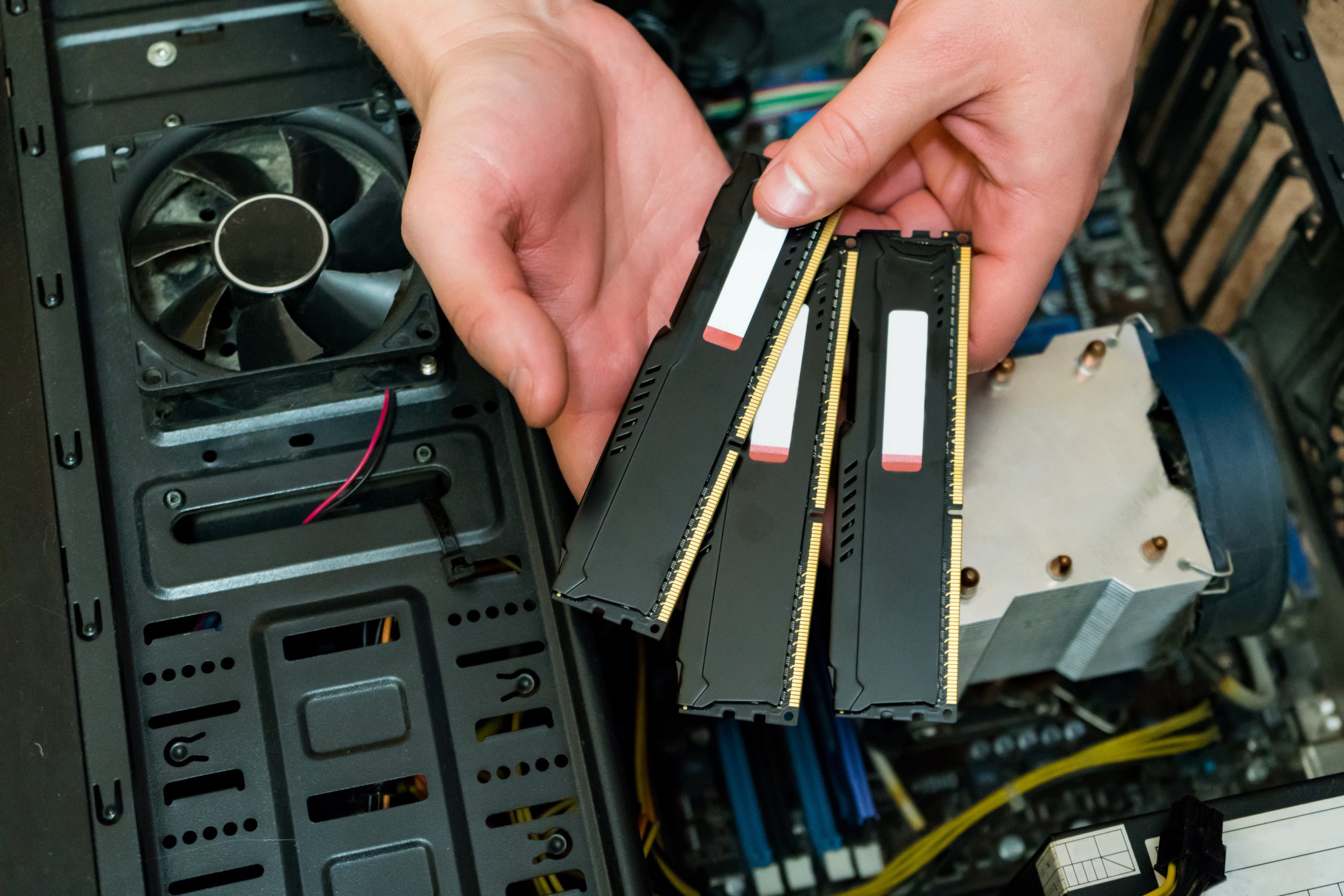 man is holding a ram on a computer background Technician holding RAM sticks for upgrading a desktop computer.