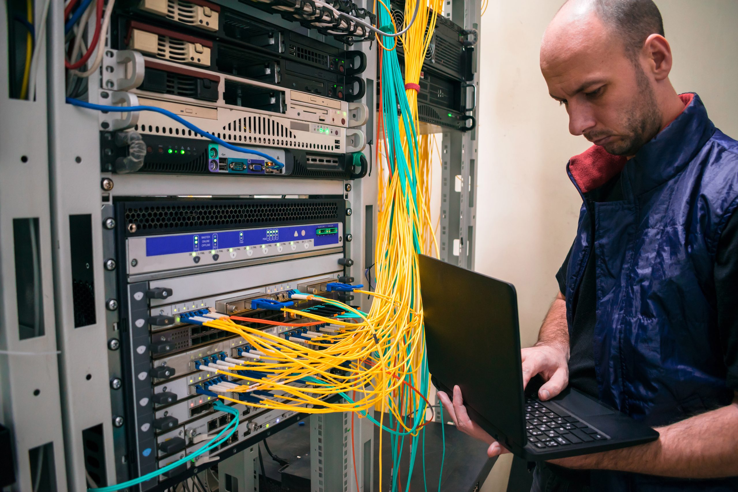Expert Network Installation and Troubleshooting Services IT technician working on a server rack with colorful network cables, representing professional network installation and troubleshooting services.