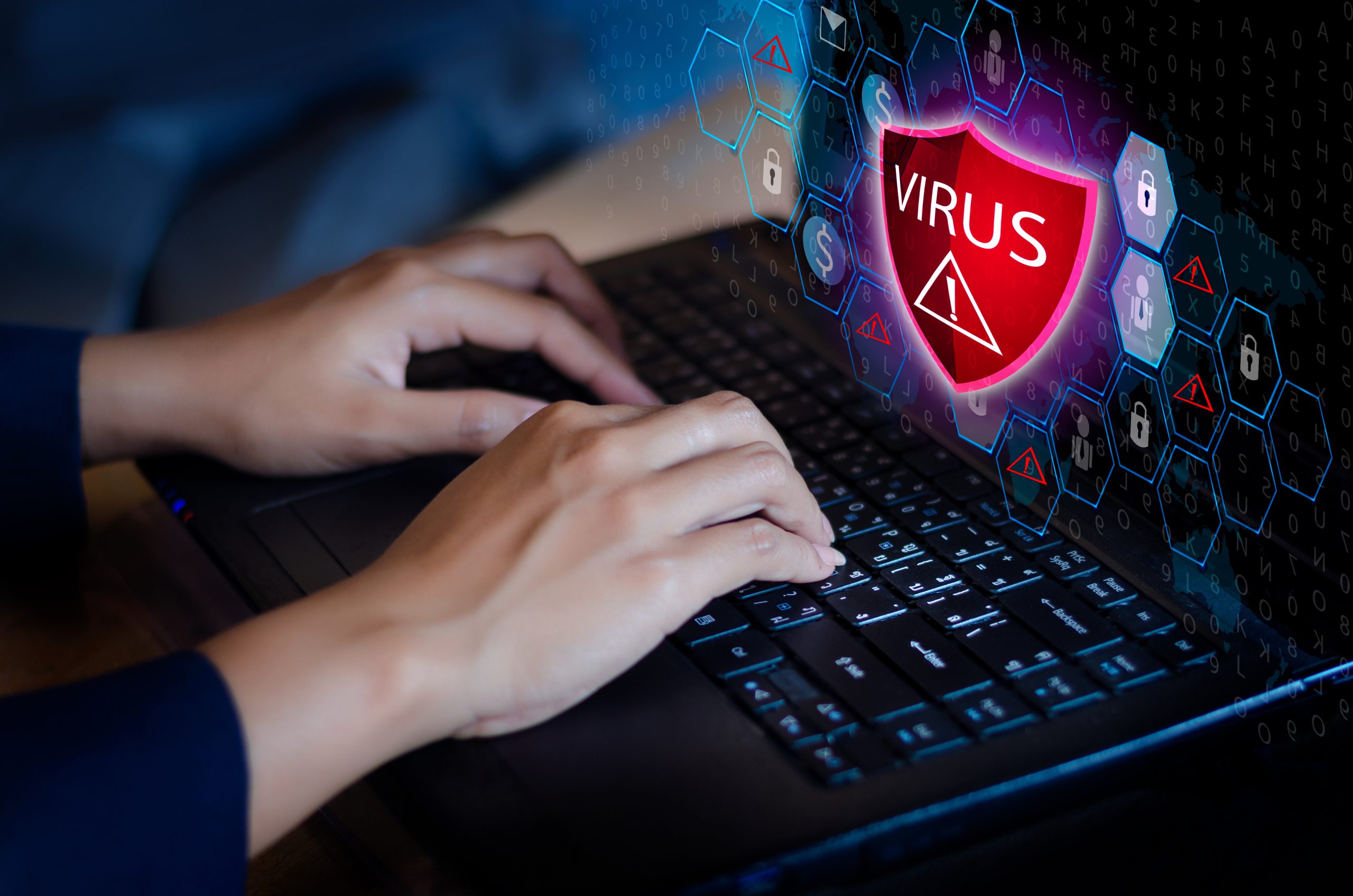 Cybersecurity and Virus Protection Concept Hands typing on a laptop keyboard with a digital shield icon labeled 'Virus' representing cybersecurity and virus protection.
